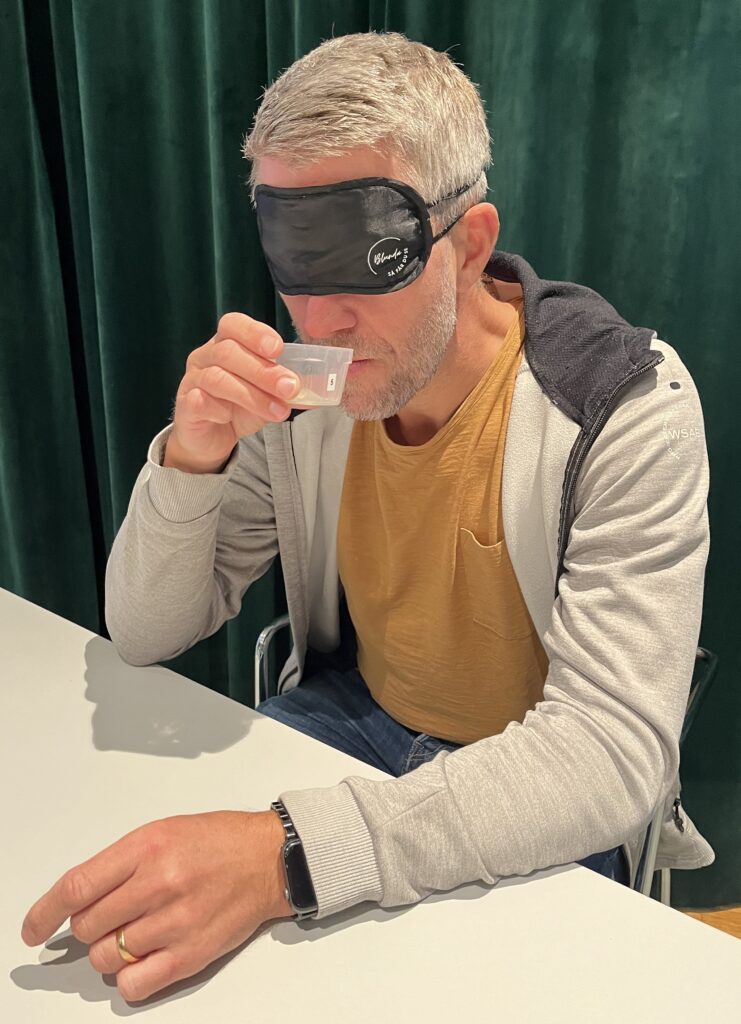 En person med ögonbindel försöker identifiera en lukt i en burk.