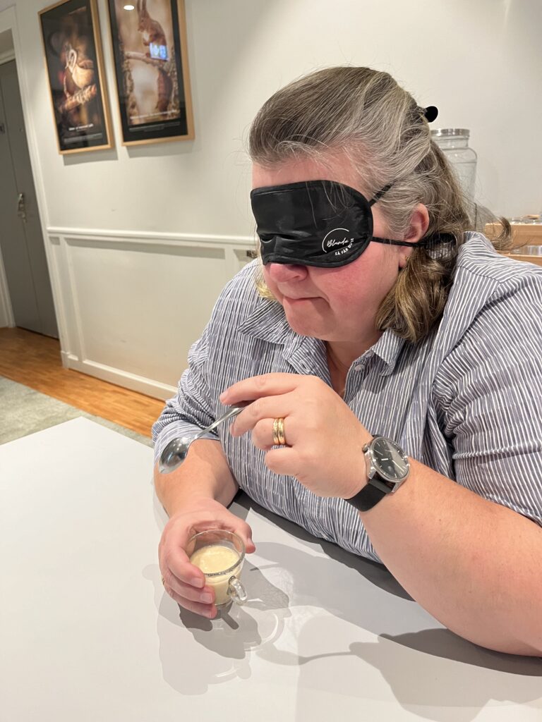 Bild från eventet Sinnesjakt: En person med ögonbindel identifierar olika smaker i en smoothie.