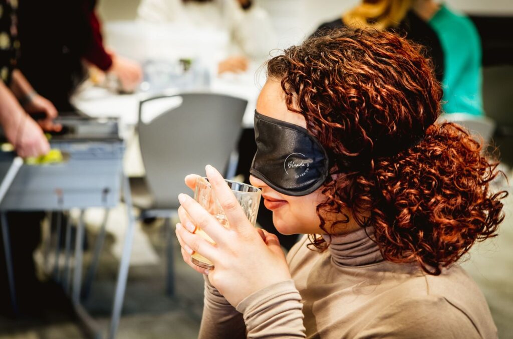 Bild från eventet Sinnesjakt: En person med ögonbindel identifierar doft i en burk.